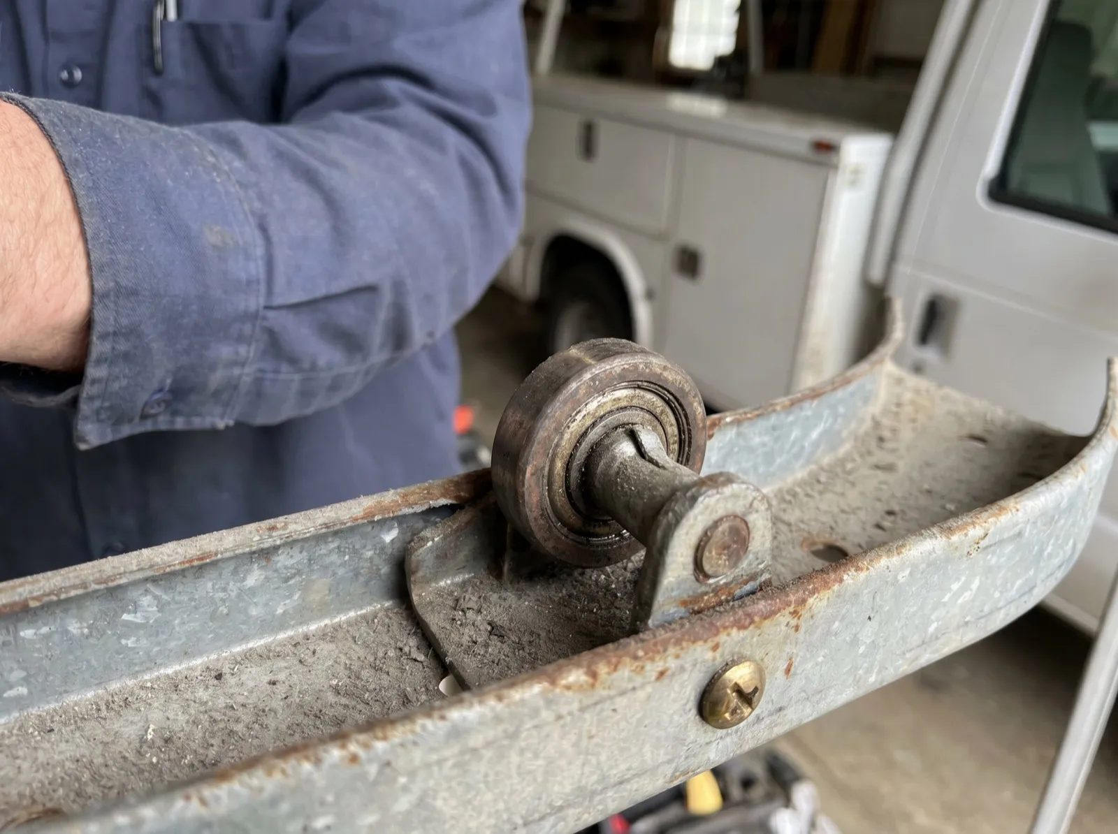 Close-up of a worn steel garage door roller seated in its curved track
